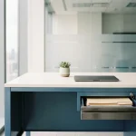 Opgeruimd modern bureau met gesloten laptop, klein potplantje en half-open la met vergrendelde vertrouwelijke documenten.
