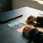 Beveiligingsanalist rangschikt kleurgecodeerde risicoматrix-kaarten op donker bureau, met laptop en dampende koffie op de achtergrond.