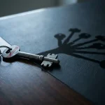 Mastersleutel op donker bureau met schaduw die vertakt in meerdere kleinere sleutels, symboliseert gelaagde toegangscontrole.