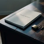 Pentestrappport op donker bureau naast een open hangslot, met een subtiele scheur in het oppervlak die verborgen kwetsbaarheden symboliseert.